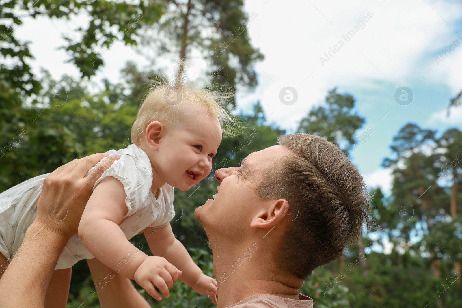 Photo of Father with his cute baby spending time together outdoors, low angle view