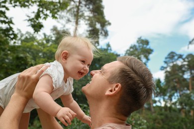 Father with his cute baby spending time together outdoors, low angle view