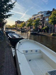 Photo of Leiden, Netherlands - August 1, 2022: Picturesque view of city canal with moored boats and beautiful buildings