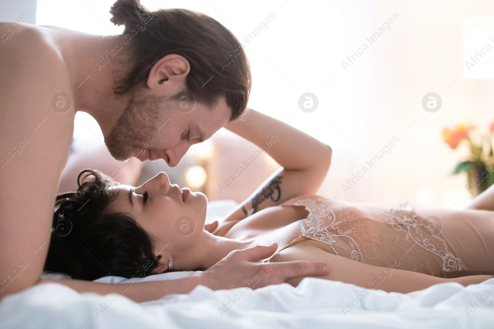 Photo of Lovely young couple being intimate on bed at home