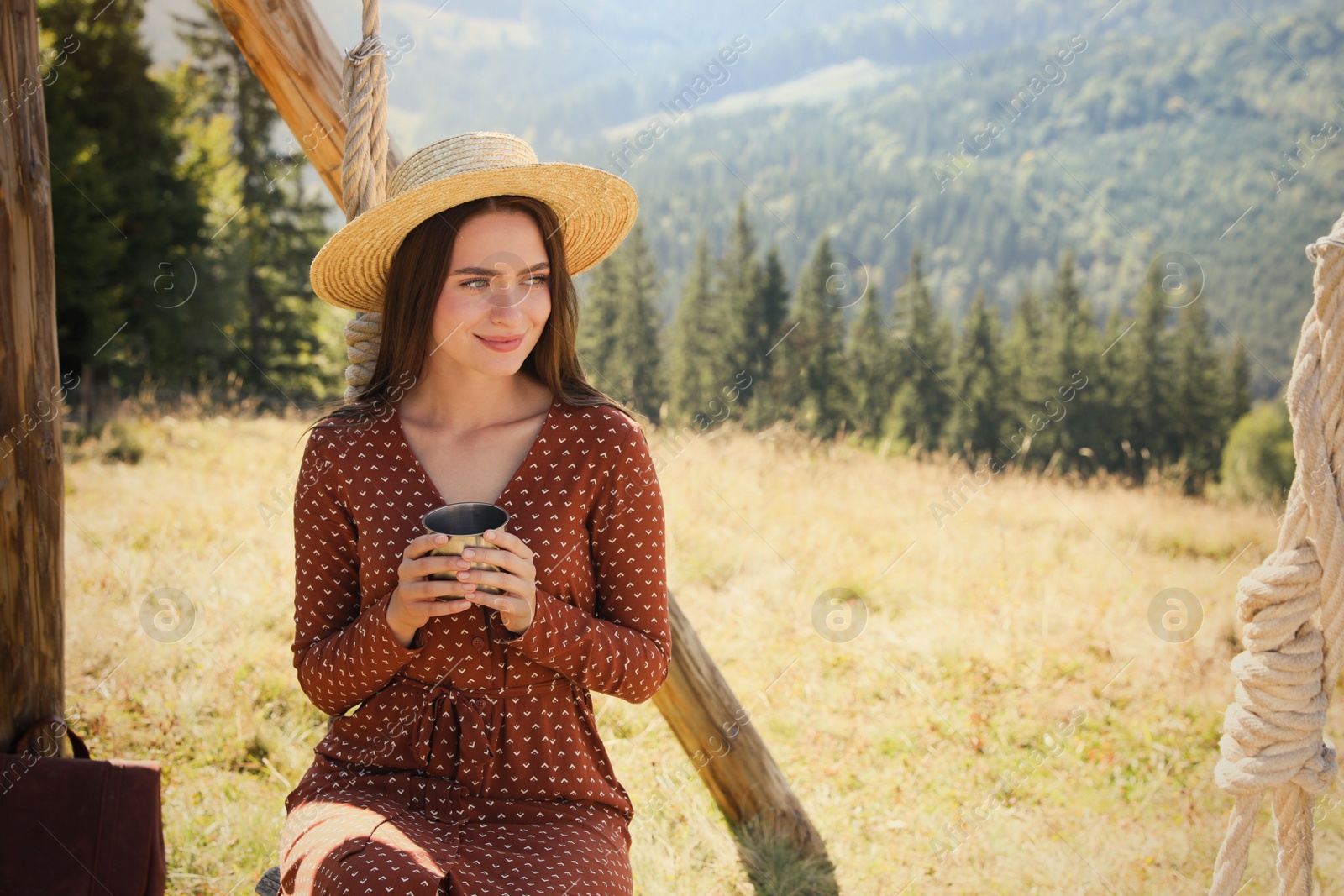 Photo of Young woman with hot drink resting outdoors on sunny day