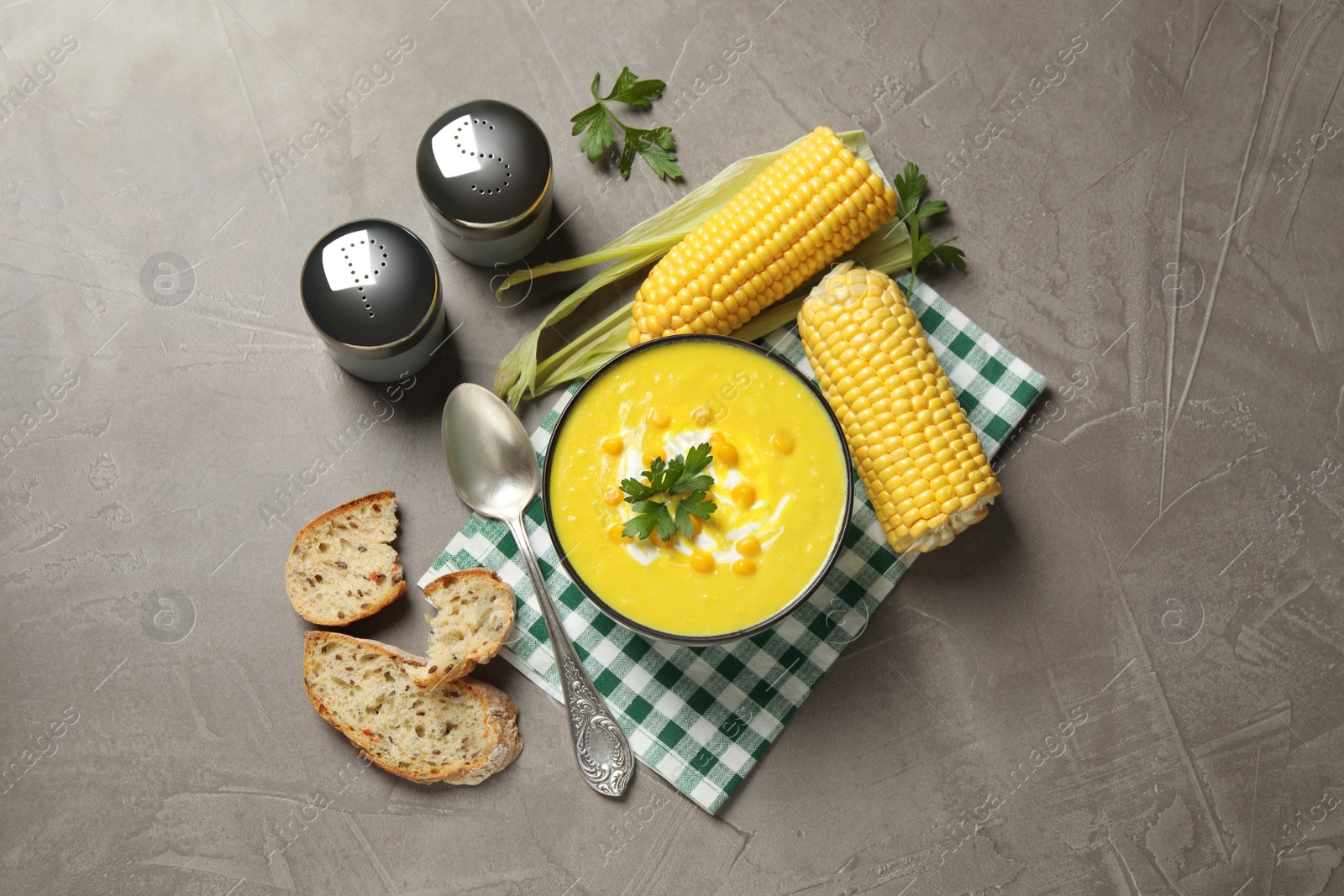 Photo of Delicious creamy corn soup served on grey table, flat lay