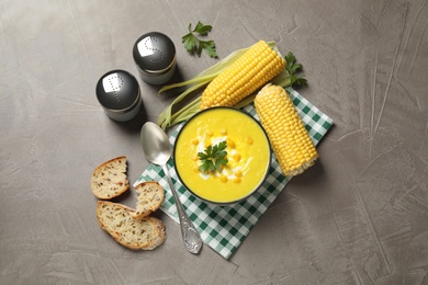 Delicious creamy corn soup served on grey table, flat lay