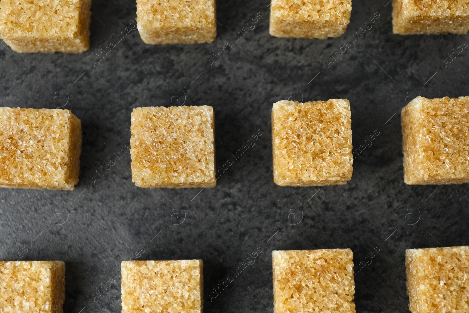 Photo of Brown sugar cubes on grey table, flat lay