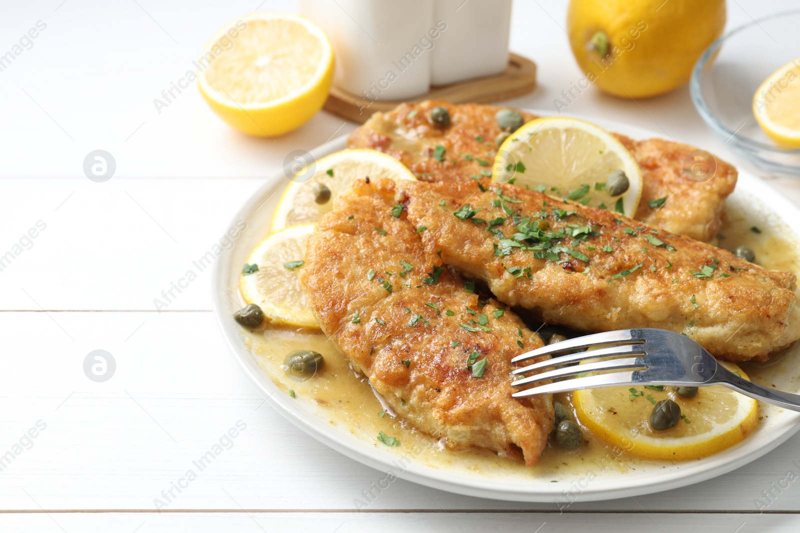 Photo of Delicious chicken piccata served on white wooden table, closeup