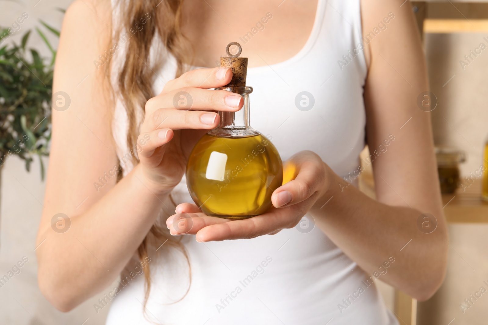 Photo of Young woman holding bottle of fresh olive oil, closeup