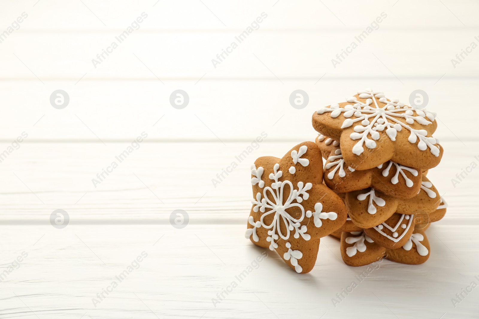 Photo of Tasty Christmas cookies with icing on white wooden table. Space for text