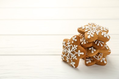 Photo of Tasty Christmas cookies with icing on white wooden table. Space for text