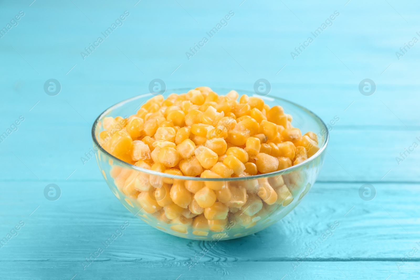 Photo of Frozen sweet corn on light blue wooden table. Vegetable preservation