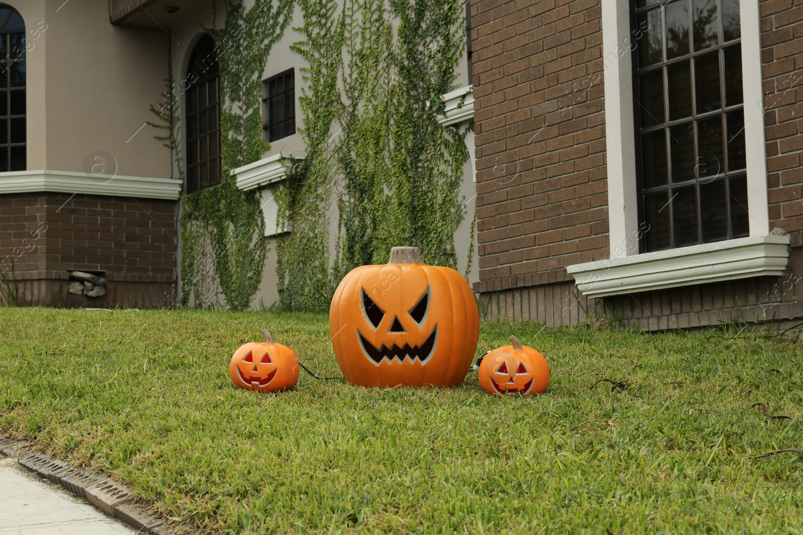 Photo of Ceramic Jack O'Lanterns on front lawn of house. Traditional Halloween decor