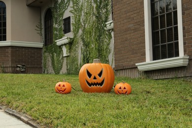 Ceramic Jack O'Lanterns on front lawn of house. Traditional Halloween decor