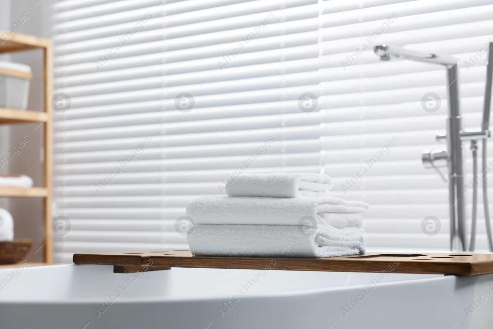 Photo of Stacked bath towels on tub tray in bathroom