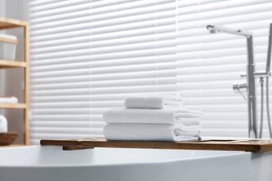 Stacked bath towels on tub tray in bathroom