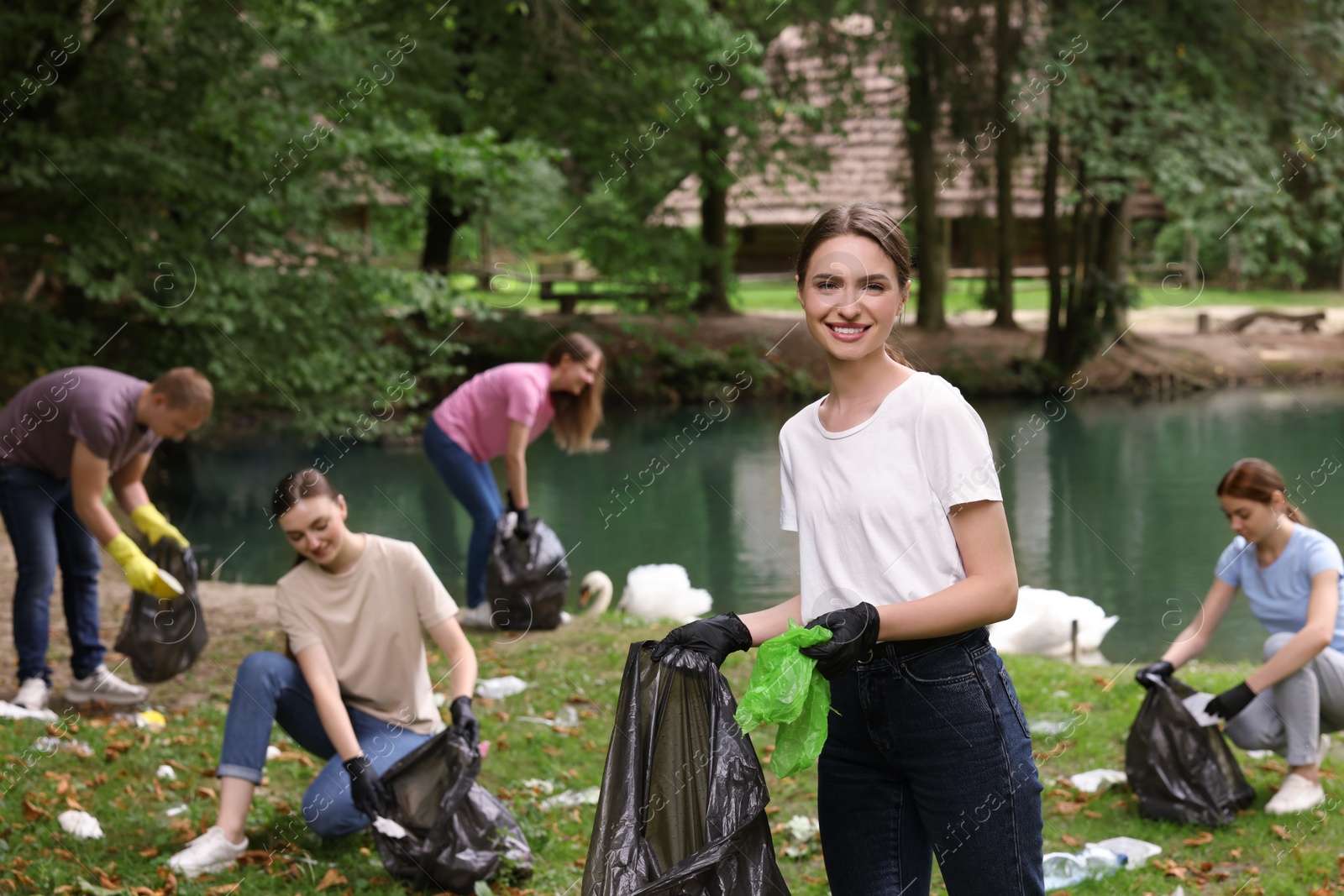 Photo of Group of people with plastic bags collecting garbage in park