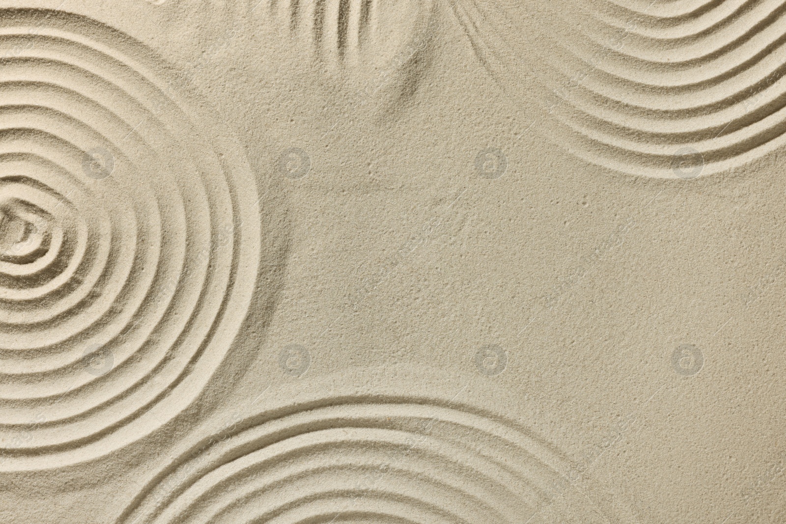 Photo of Beautiful patterns drawn on sand, top view with space for text. Zen garden