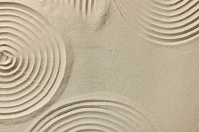 Photo of Beautiful patterns drawn on sand, top view with space for text. Zen garden