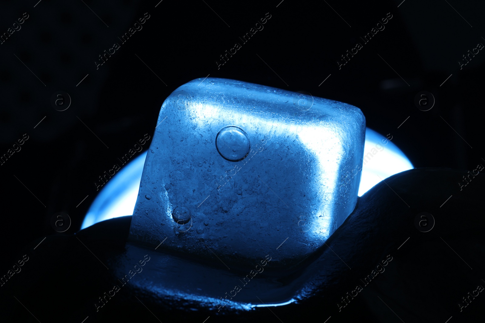 Photo of Crystal clear ice cube on dark background, closeup. Color tone effect