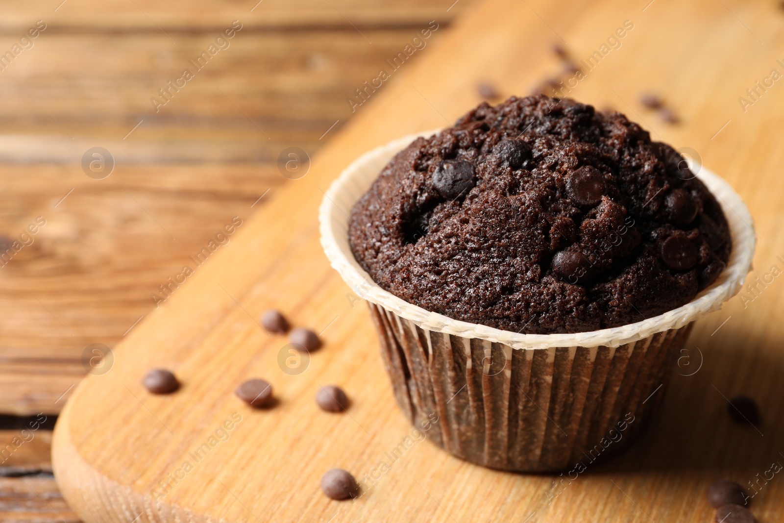 Photo of Tasty chocolate muffin on wooden table, closeup. Space for text