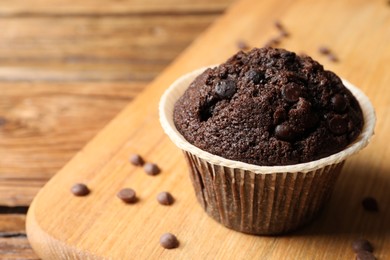 Photo of Tasty chocolate muffin on wooden table, closeup. Space for text