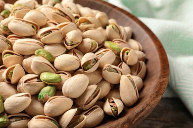 Photo of Organic pistachio nuts in plate on table, closeup