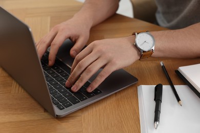 Man working on laptop at wooden desk, closeup