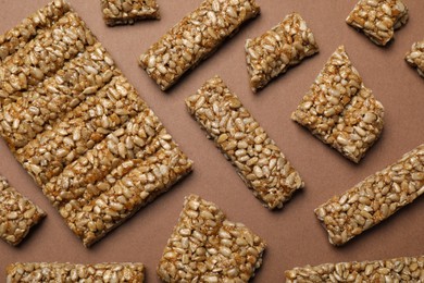 Photo of Pieces of delicious kozinaki bars on brown background, flat lay