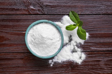 Photo of Sweet fructose powder and mint leaves on dark wooden table, flat lay