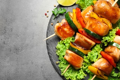 Photo of Delicious chicken shish kebabs with vegetables on grey table, top view. Space for text