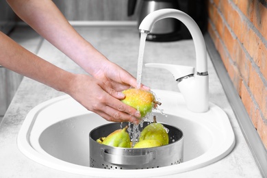 Photo of Woman washing fresh ripe pears in kitchen sink, closeup