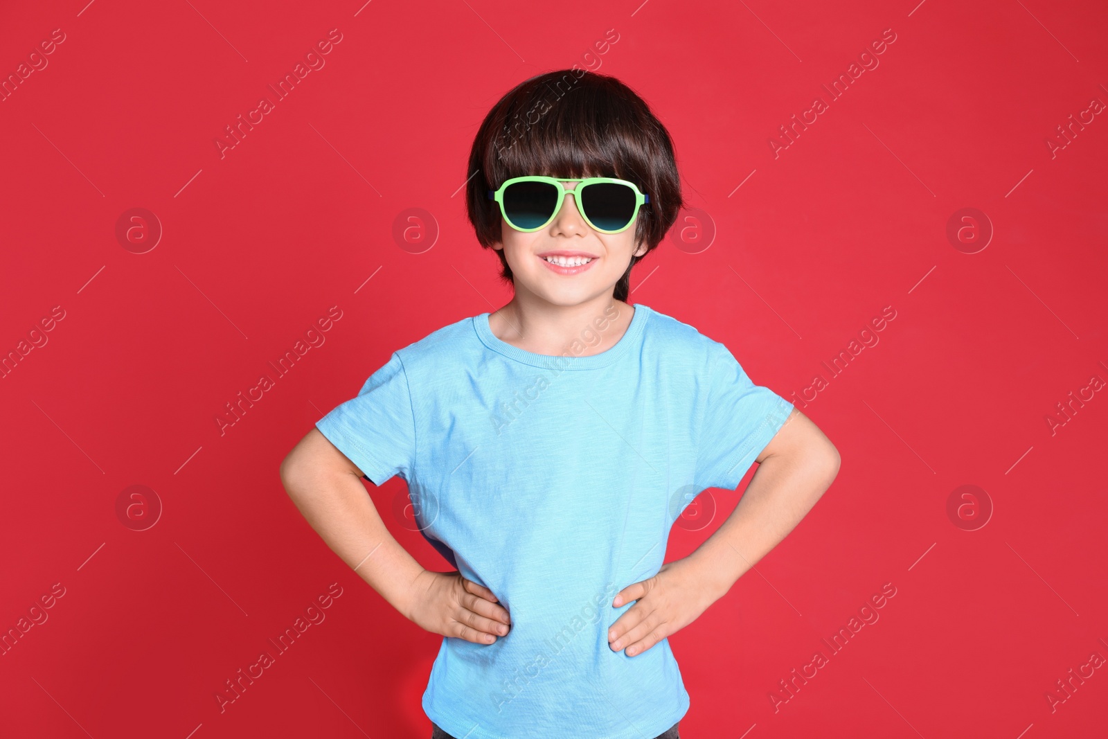 Photo of Cute little boy with sunglasses on red background