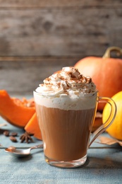 Photo of Glass cup with tasty pumpkin spice latte on wooden table