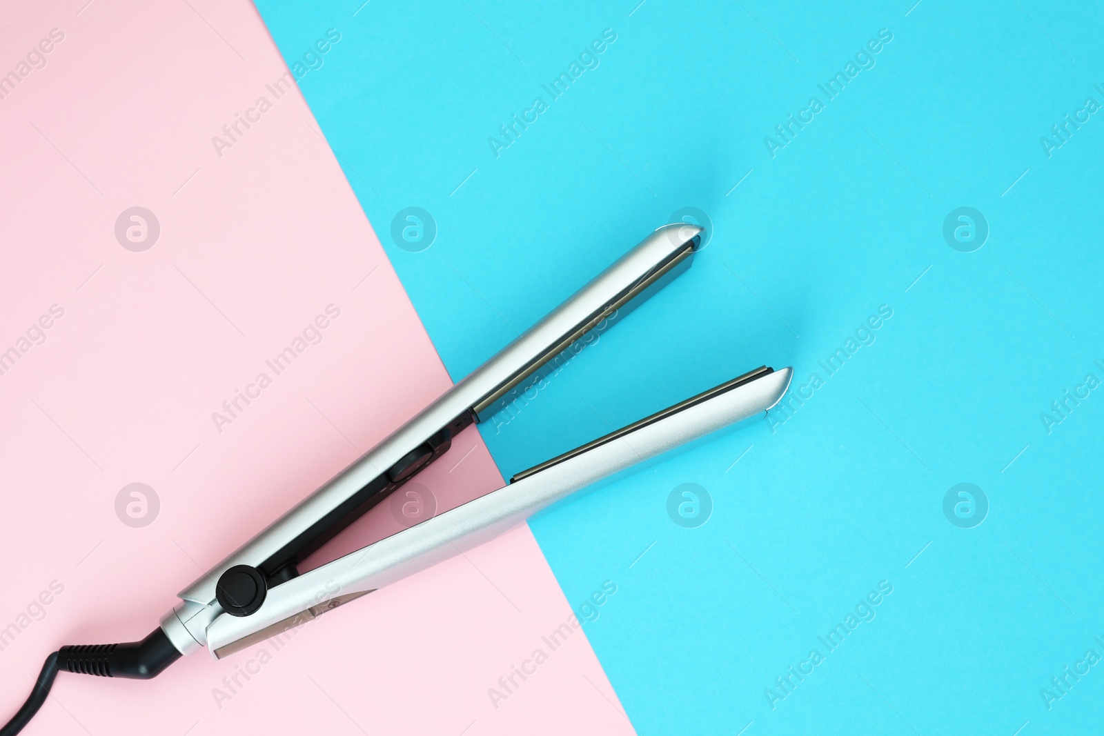 Photo of Modern hair iron for straightening on color background, top view