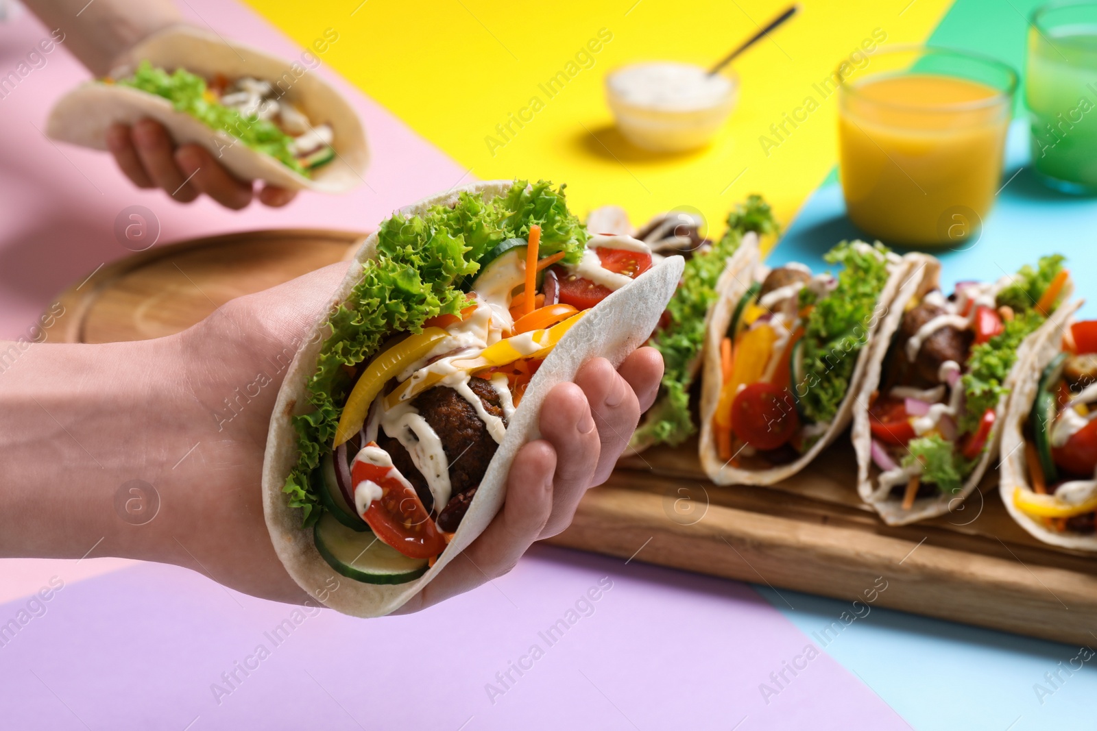Photo of Woman holding delicious taco against color background, closeup