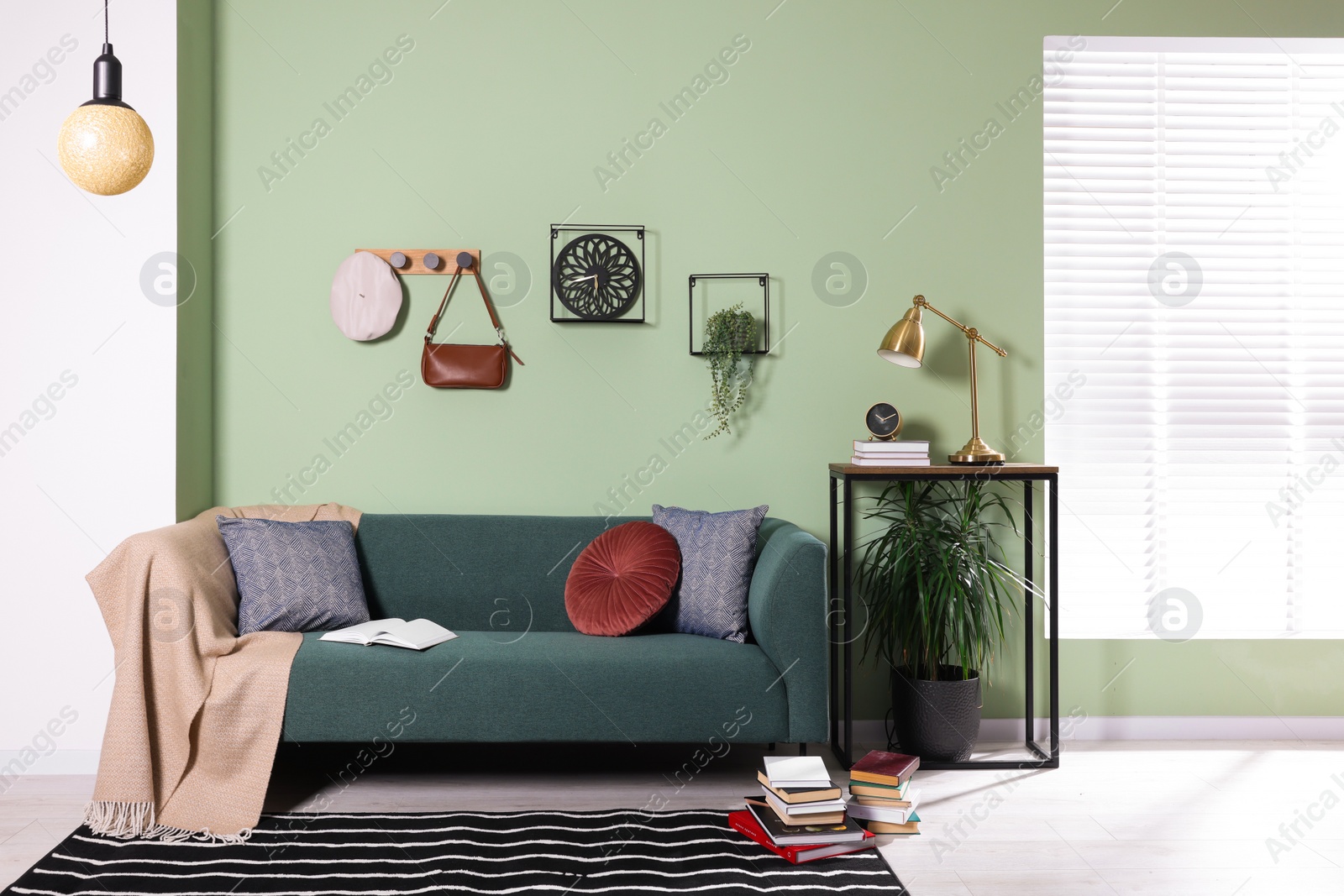 Photo of Stylish interior with comfortable sofa, blanket and cushions near console table