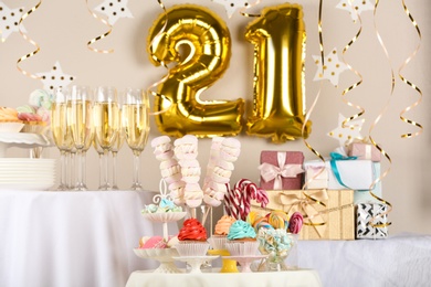 Photo of Dessert table in room decorated with golden balloons for 21 year birthday party