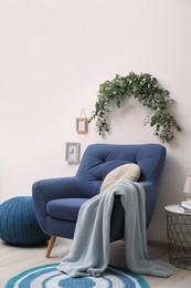 Stylish room decorated with beautiful eucalyptus garland above comfortable armchair