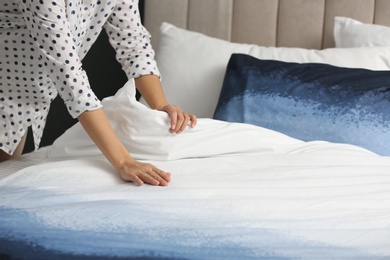 Woman making bed at home, closeup of hands