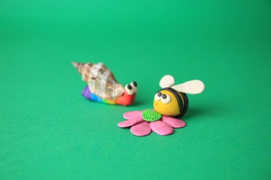 Photo of Beautiful plasticine bee with flower and snail on green background. Children's handmade ideas