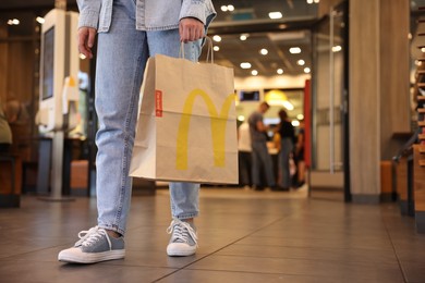Photo of Lviv, Ukraine - September 26, 2023: Woman with McDonald's paper bag in cafe, closeup. Space for text