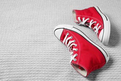 Pair of new stylish red sneakers on light grey fabric. Space for text