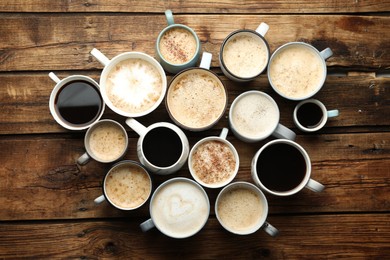 Photo of Many cups of different coffees on wooden table, flat lay