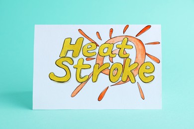 Card with words Heat Stroke on turquoise background