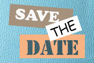 Image of Phrase SAVE THE DATE on light blue leather, top view  