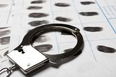 Photo of Police handcuff and criminal fingerprints card, closeup