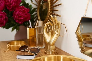 Photo of Composition with gold accessories and flowers on dressing table near white wall