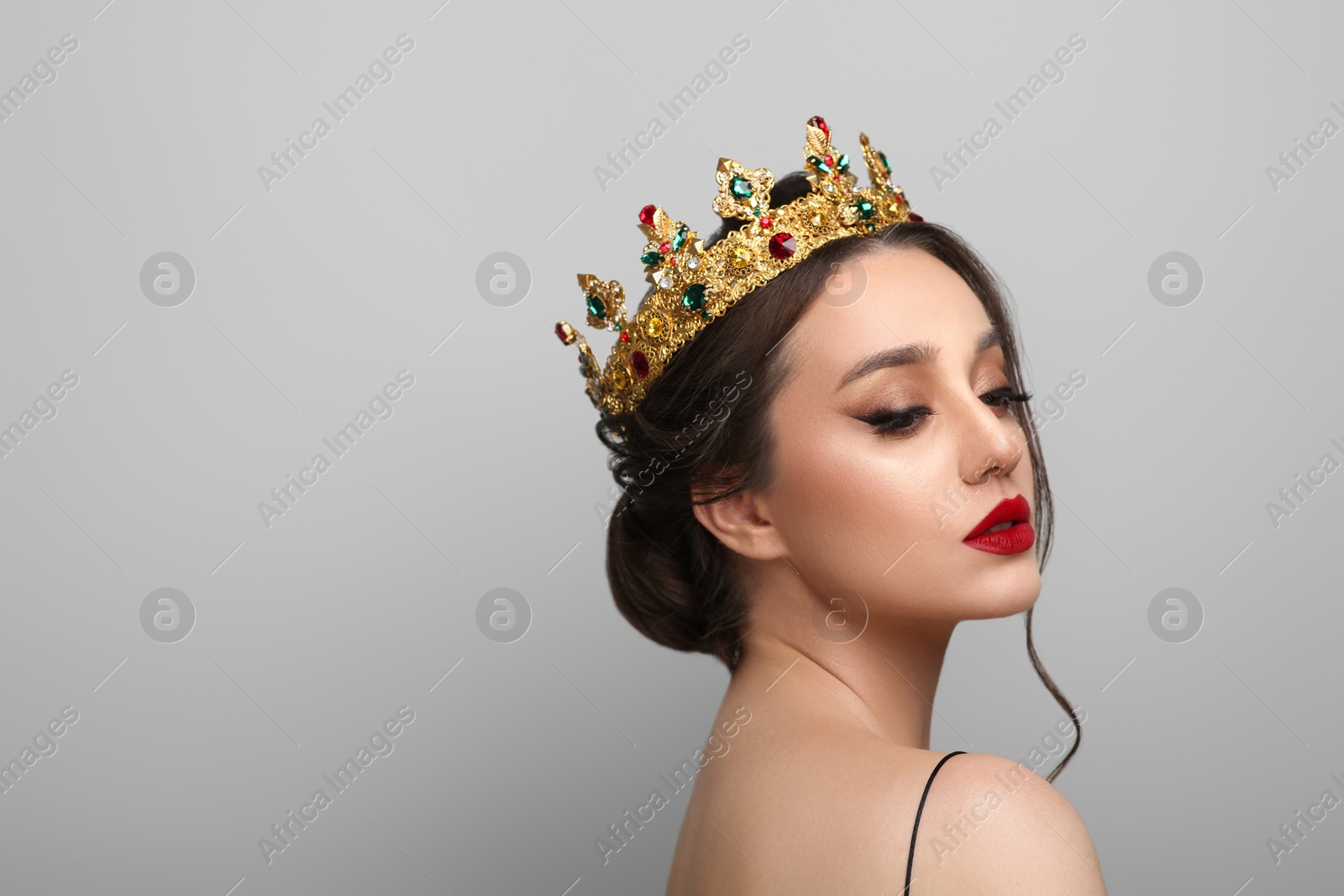 Photo of Beautiful young woman wearing luxurious crown on light grey background, space for text