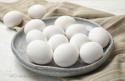 Photo of Plate with raw chicken eggs on wooden table