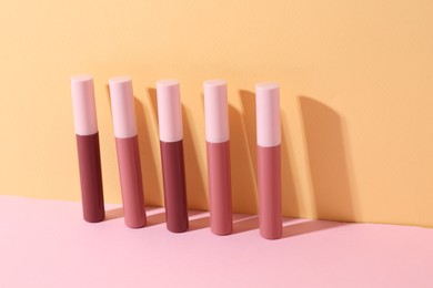 Photo of Many different lip glosses on color background