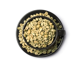 Cup and plate with green coffee beans on white background, top view