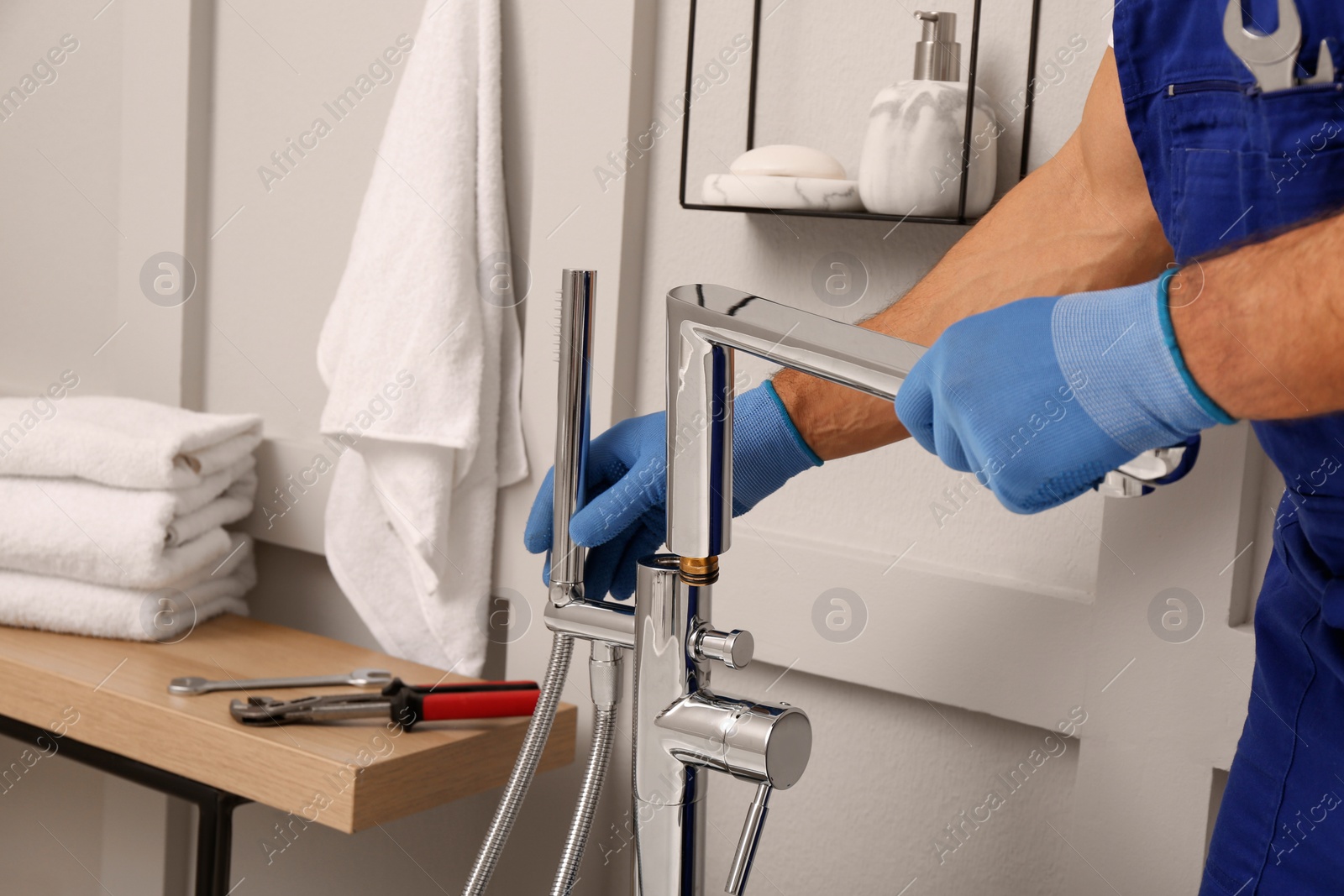 Photo of Professional plumber installing water tap in bathroom, closeup